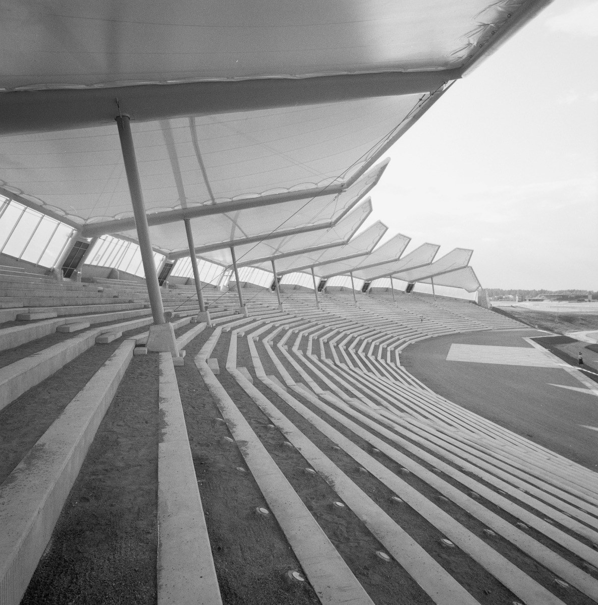 Mustavalkokuvassa katettua nousevaa katsomoa sivulta kuvattuna.