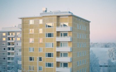 Kahden asuinkerrostalon ylimmät kerrokset talvisessa udussa.