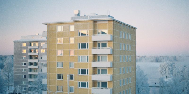 Kahden asuinkerrostalon ylimmät kerrokset talvisessa udussa.